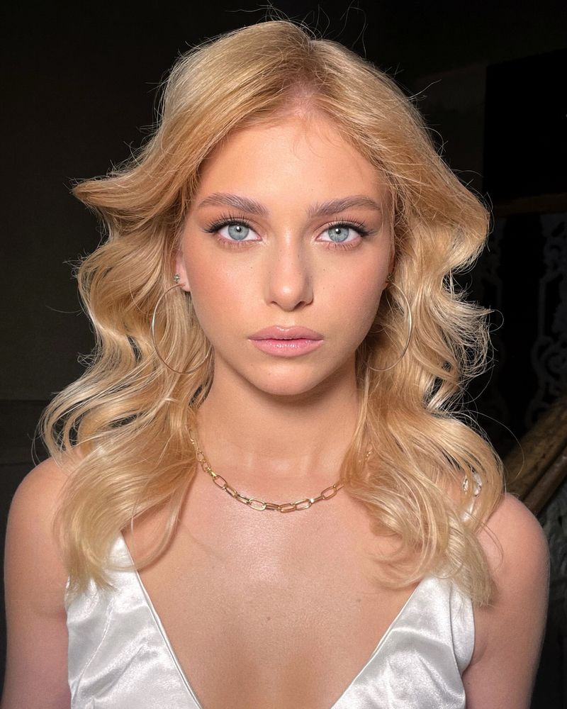 Coafură cu bucle blonde voluminoase și machiaj luminos